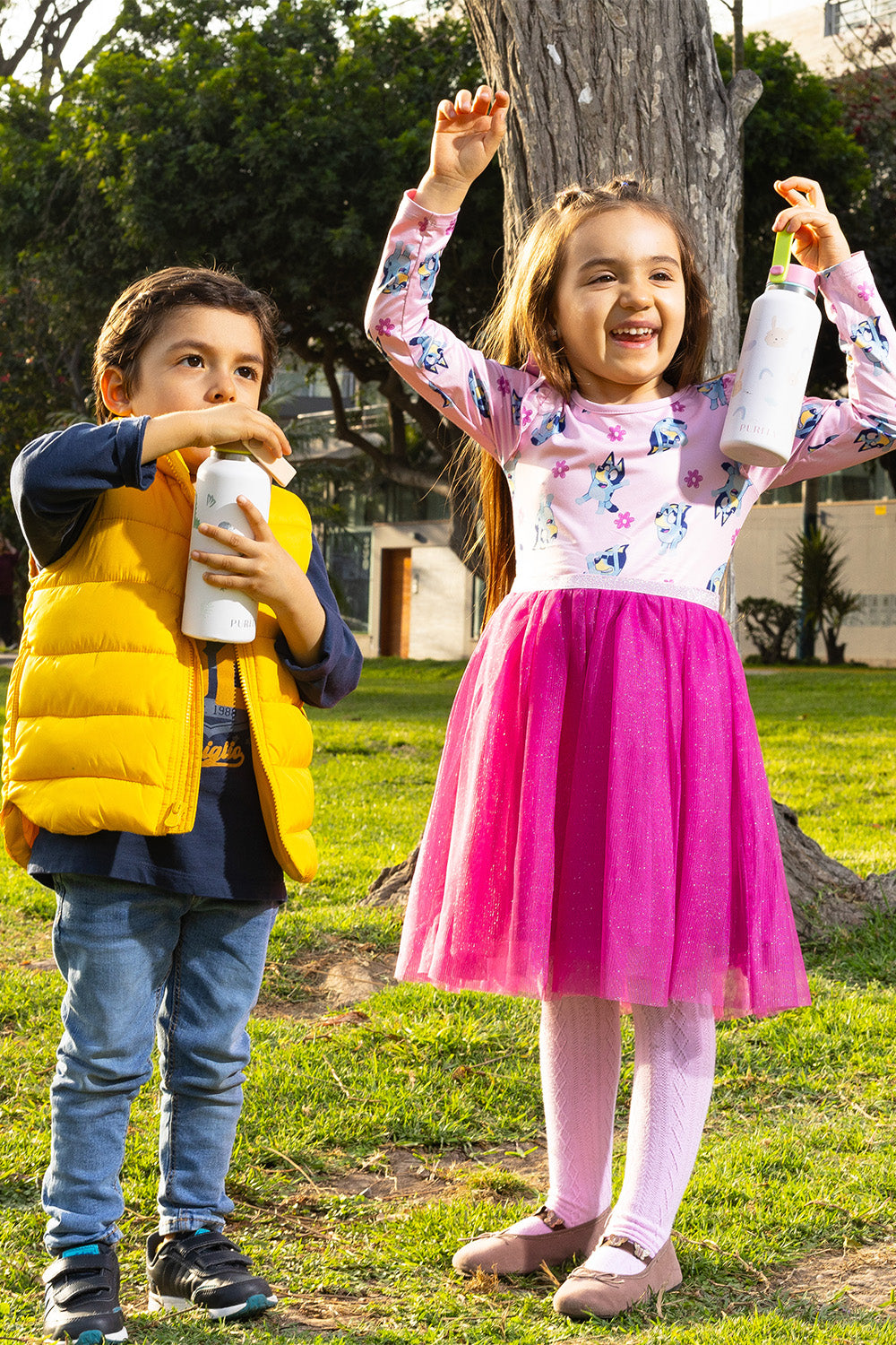 Una niña y un niño sonríen en un parque. Cada uno sostiene un tomatodo bunny.